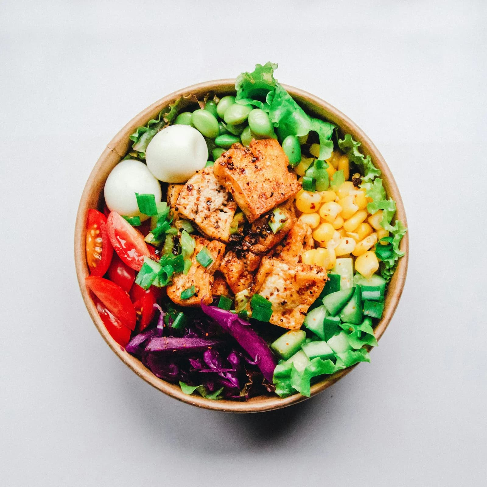 Keto-vriendelijke maaltijd met avocado, ei en groene groenten op een houten tafel